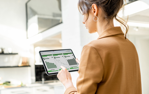 Frau schaut auf ein Tablet mit Verbrauchsgrafiken