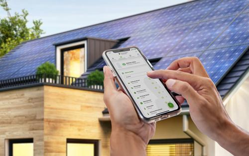 Smartphone vor einem Haus mit PV-Anlage